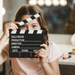 close-up-girl-looking-through-clapper-board