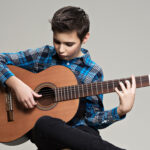 Caucasian  boy playing on acoustic guitar. Teenager boy with classic wooden guitar